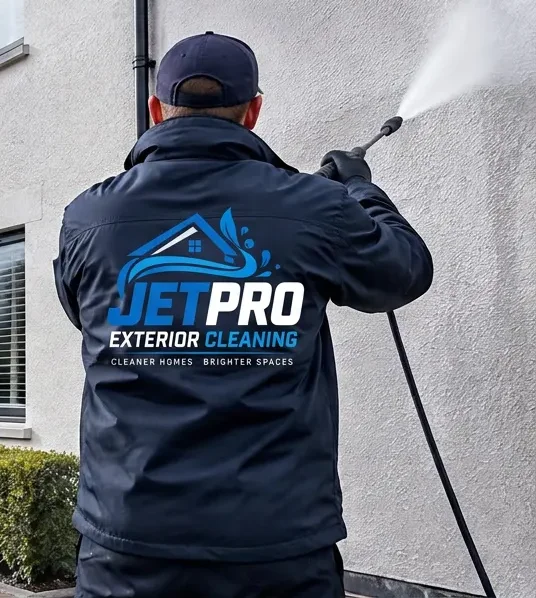 JETPRO technician in branded workwear jet washing a rendered wall